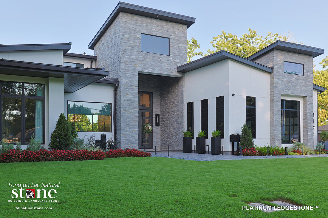 Gray natural ledgestone on a modern home with stepped rooflines and a green lawn, featuring Fond du Lac Platinum Ledgestone.