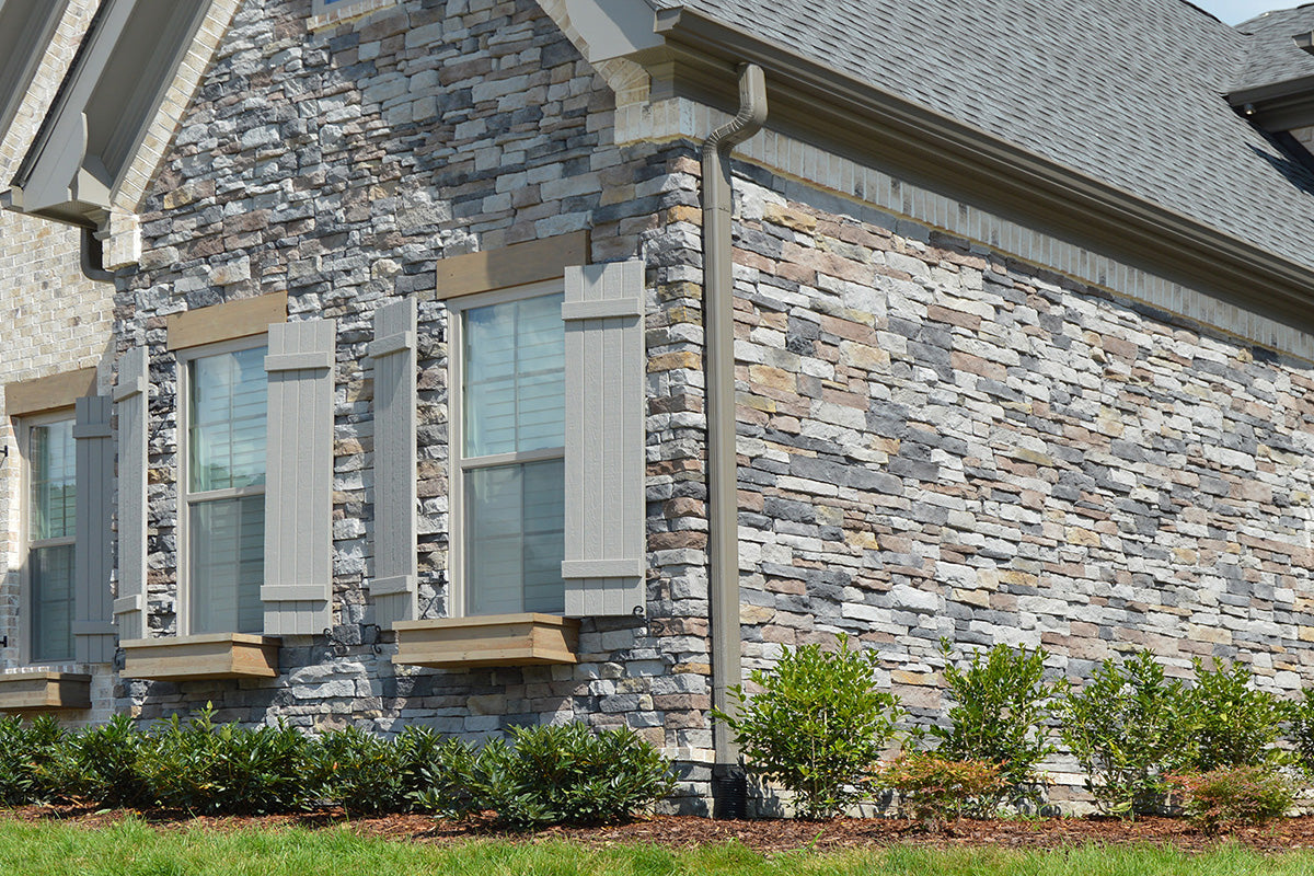 Stone facade of a building with windows and greenery