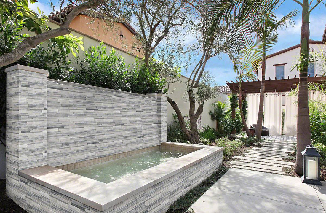 Alaska Gray 3D Honed marble panels around an outdoor fountain and garden wall.