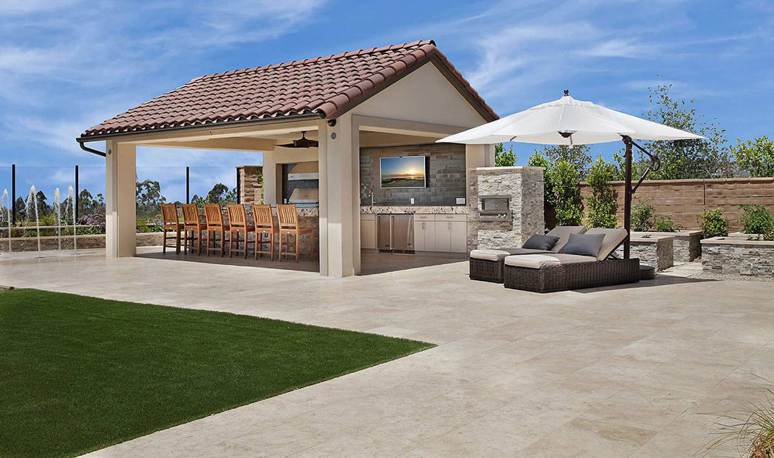 Light natural stone kitchen and bar under a tile-roofed patio pavilion, featuring MSI® Rockmount Silver Travertine.
