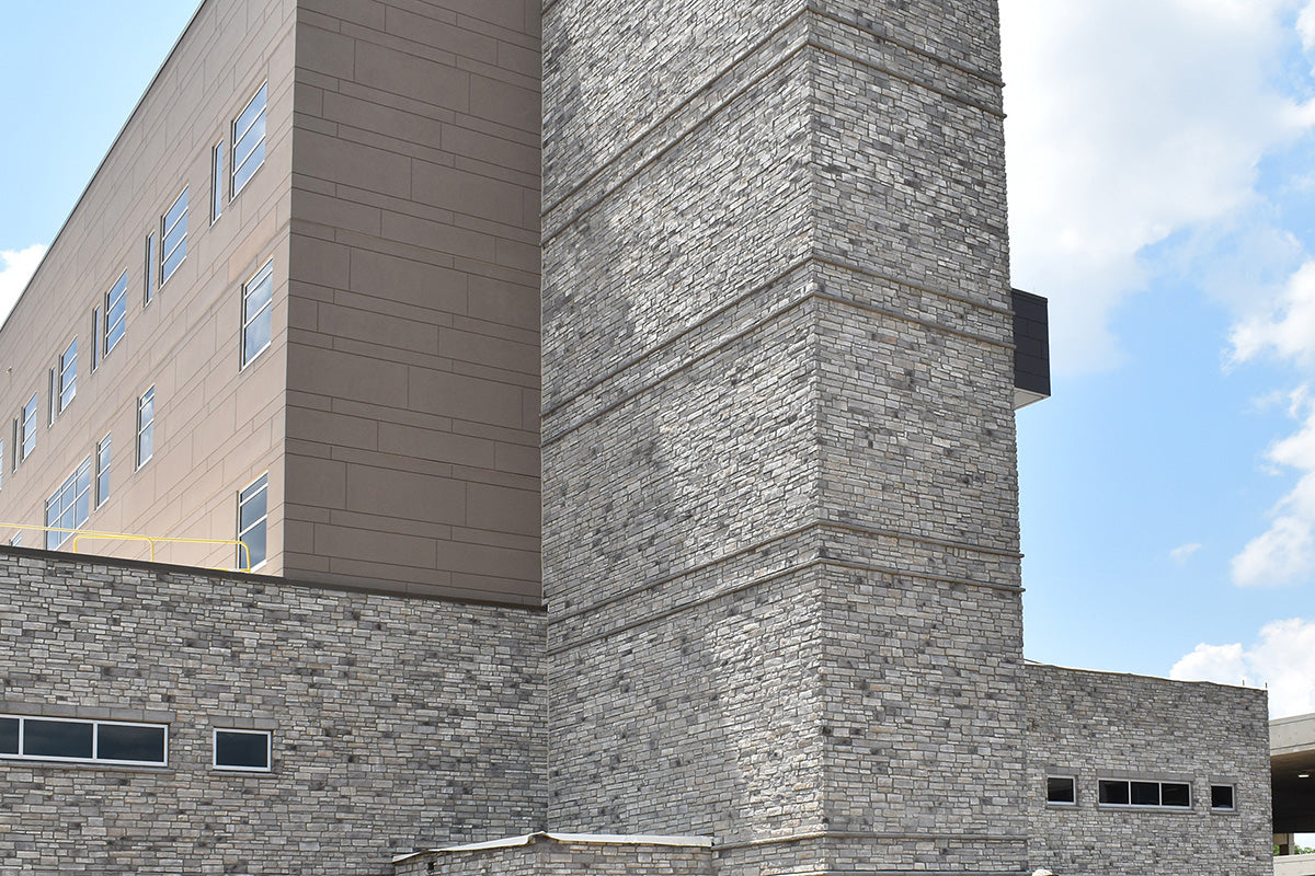 Building exterior with stone and concrete walls under a blue sky.