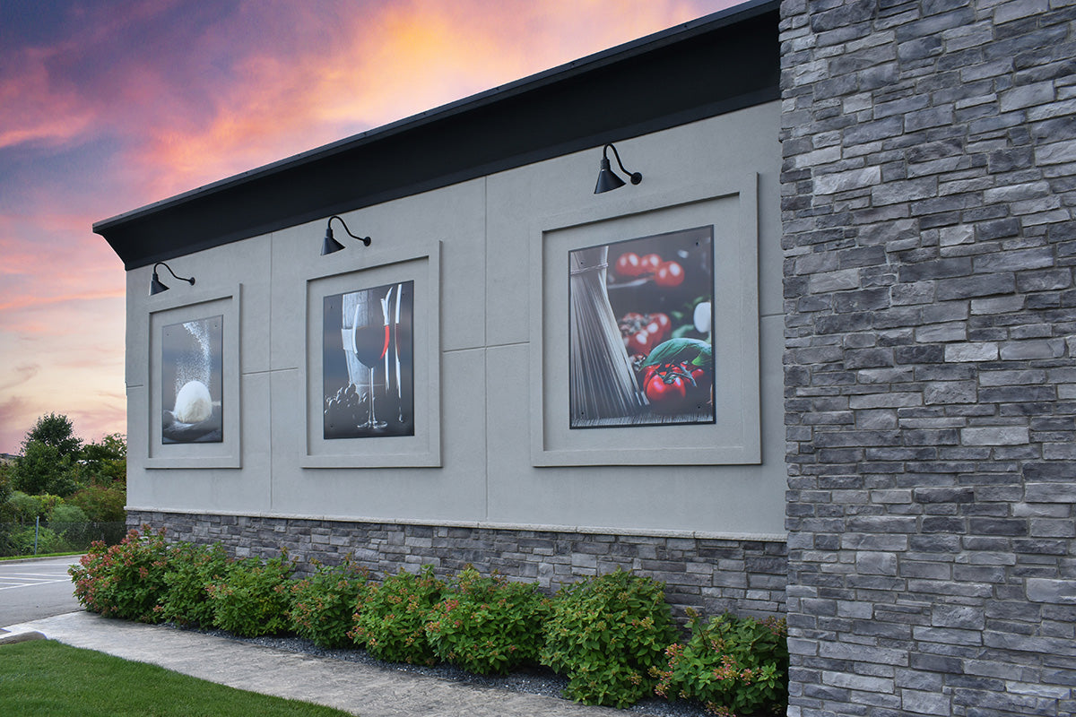 Framed artworks on a building exterior with a colorful sky.