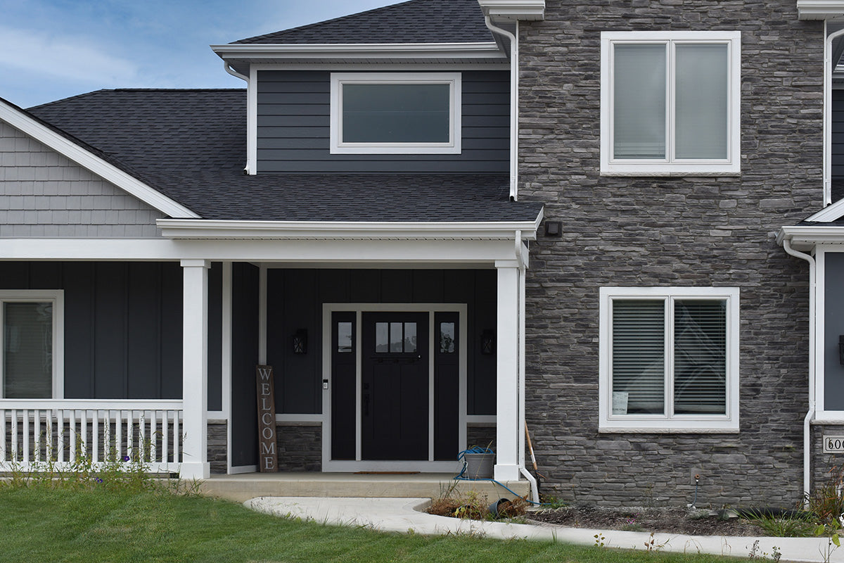 Two-story house with gray siding and white trim on a clear day.
