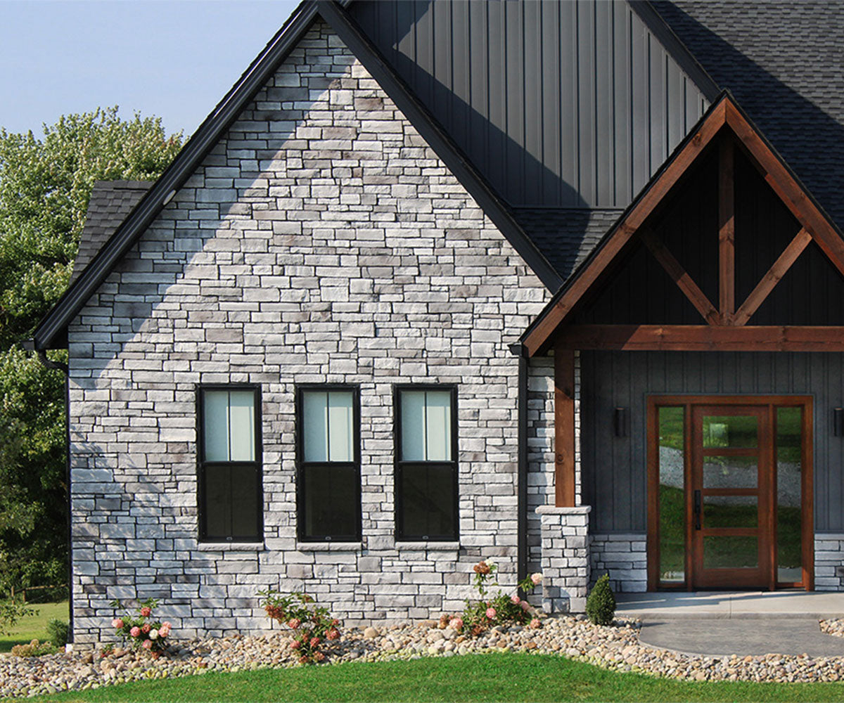 House with stone facade and wooden door, surrounded by greenery