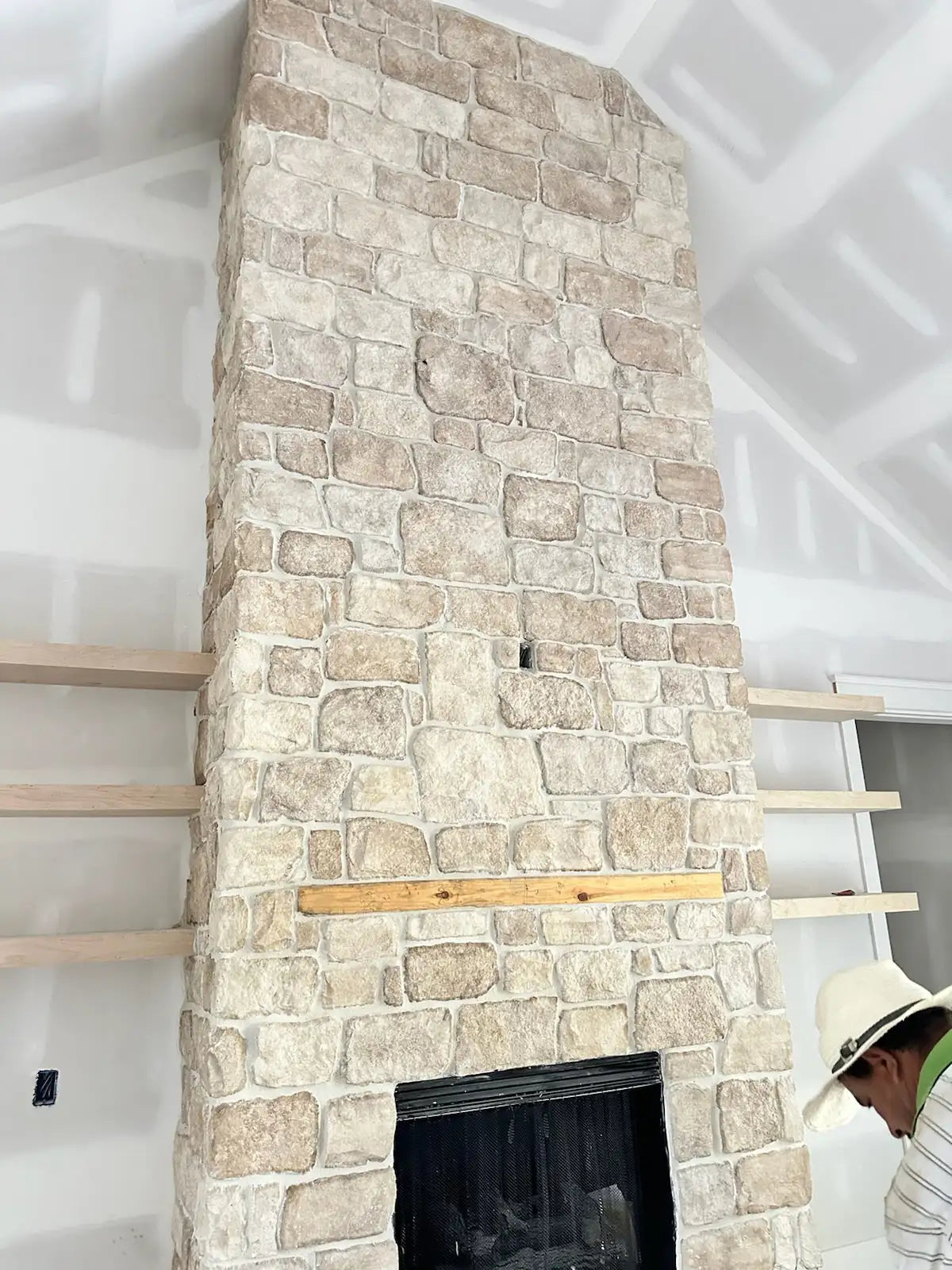 Stone fireplace with wooden mantel and hearth, light beige color.