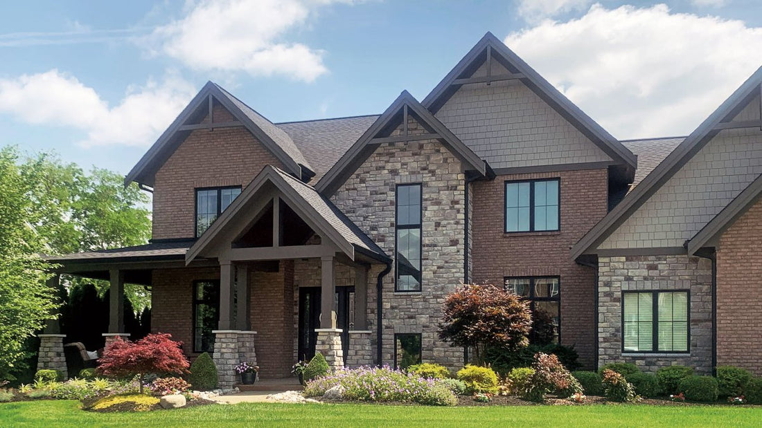 Earth-toned stone home exterior with timber-framed gables and a landscaped front garden, featuring StoneCraft Hamilton Heritage.