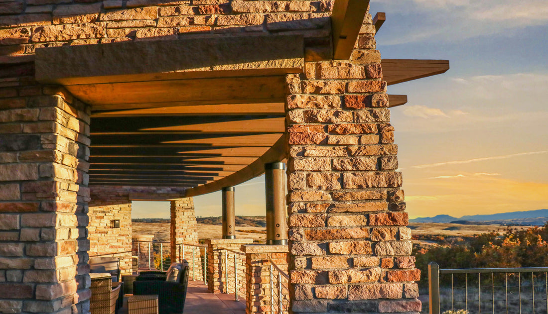 Warm ledgestone columns and walls along a timber-roofed patio in evening light, featuring Sunset Stone Cheyenne Ledge.