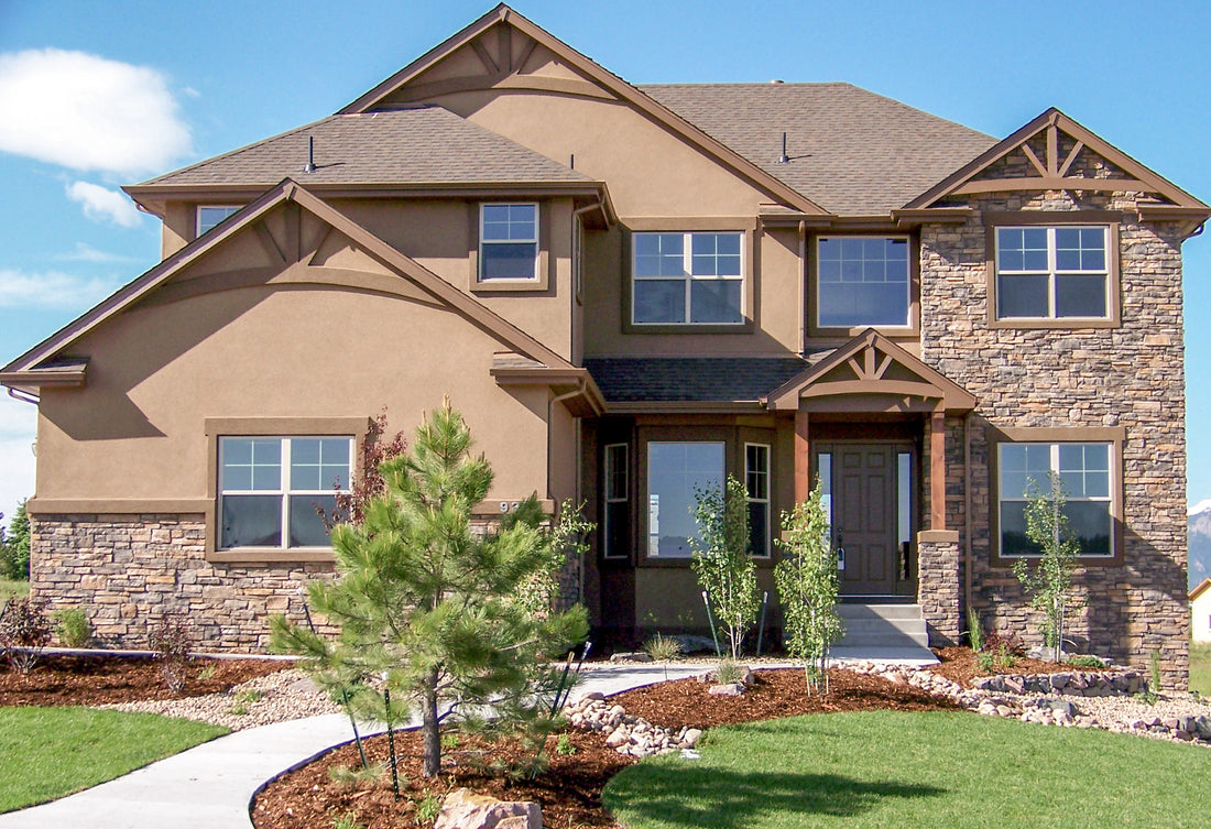 Brown dry-stack ledge on a two-story home with timber gables and mulched garden beds, featuring Sunset Stone Georgia Brown Dry Stack Ledge.