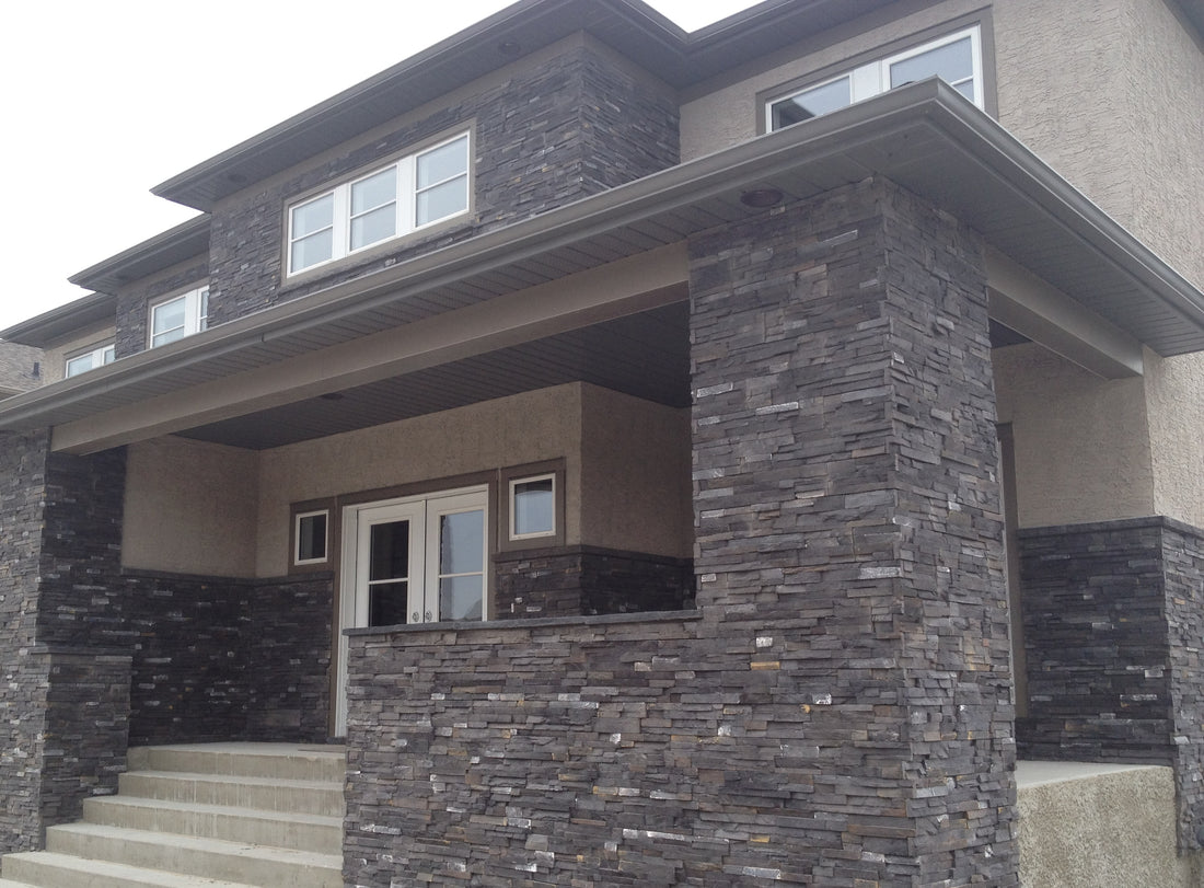 Dark stacked stone on tall porch columns and lower walls of a two-story home, featuring Sunset Stone Pinos Creek Stacked Stone.