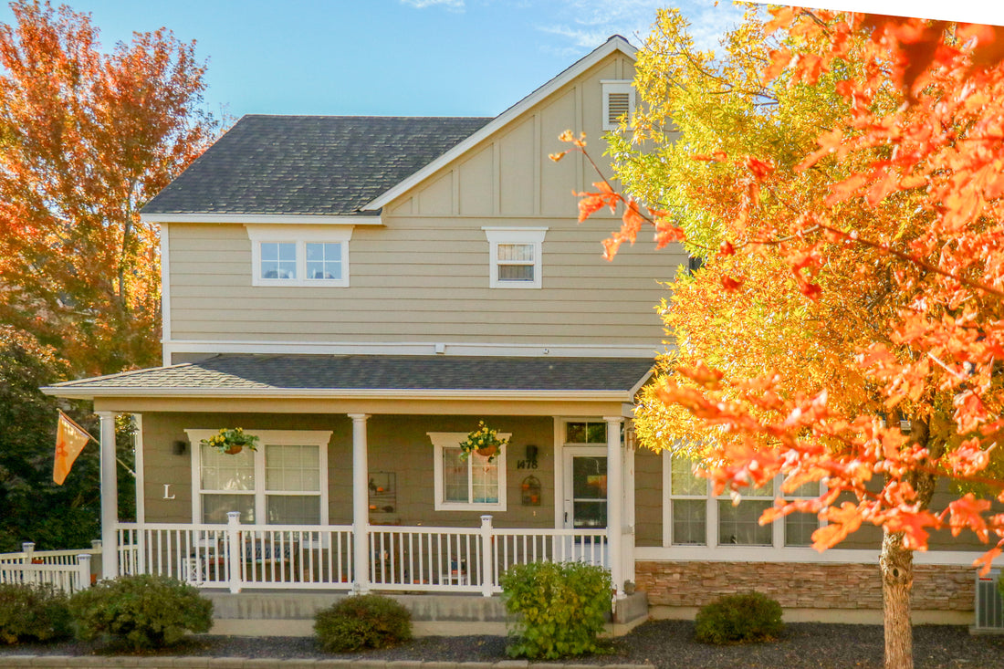 Stone foundation and porch columns on a pale-sided home with autumn foliage, featuring Sunset Stone Telluride Dry Stack Ledge.