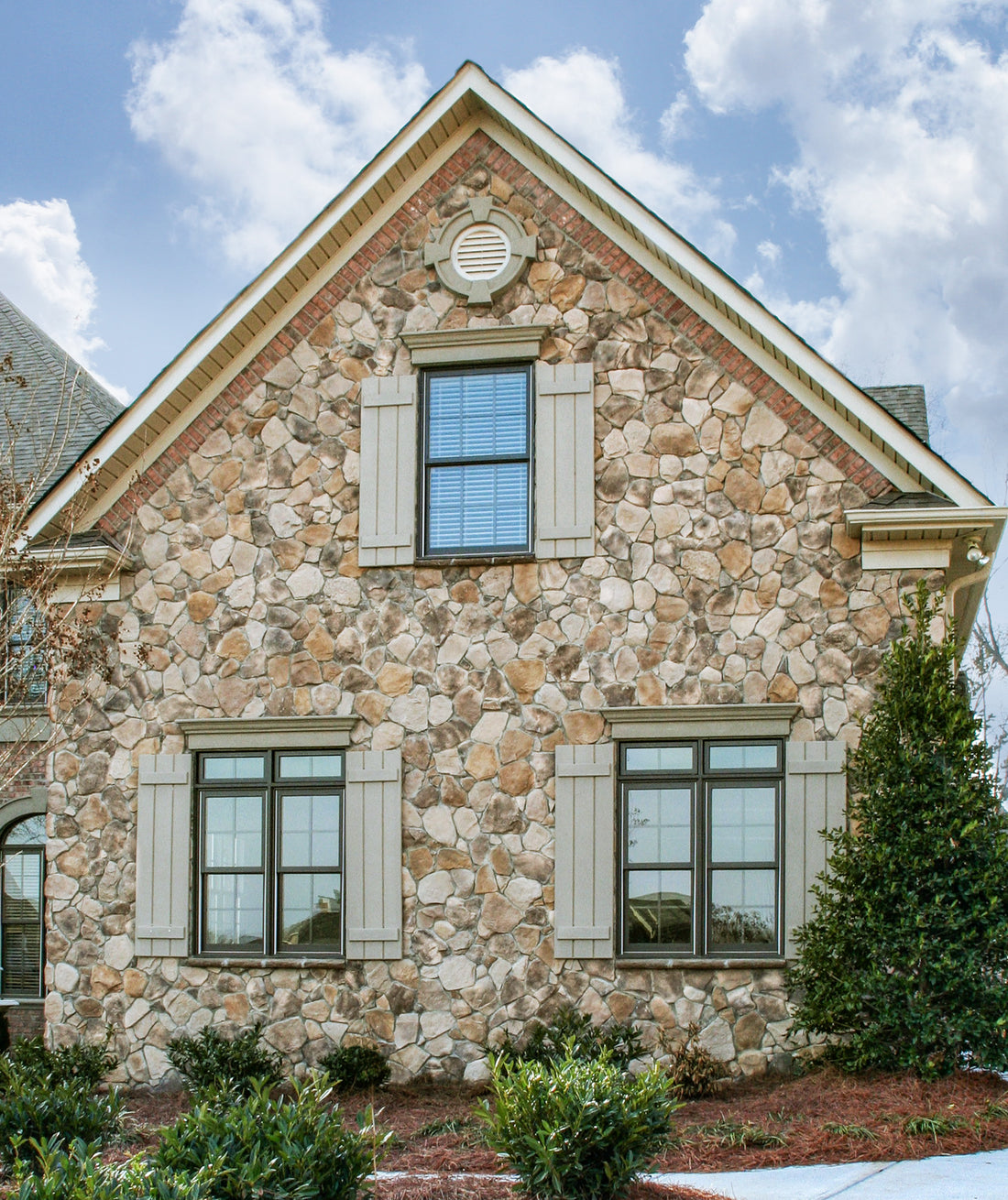 Fieldstone gable with brick window accents on a two-story home, featuring Provia Top Rock Fieldstone.
