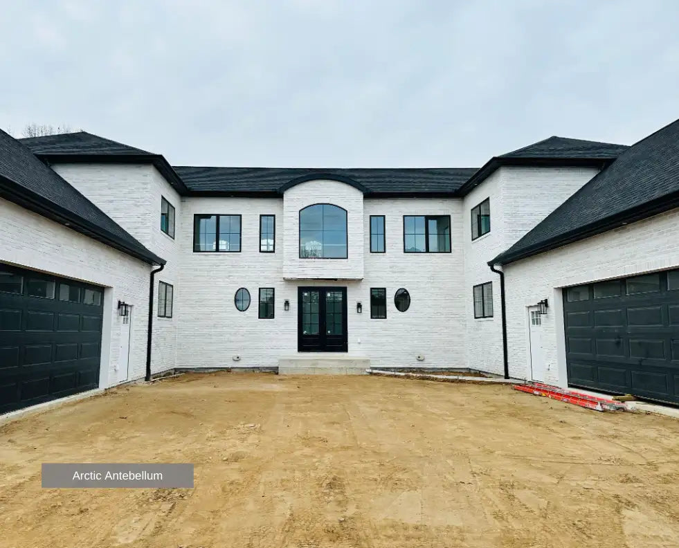 White modern house with black accents and garage doors.