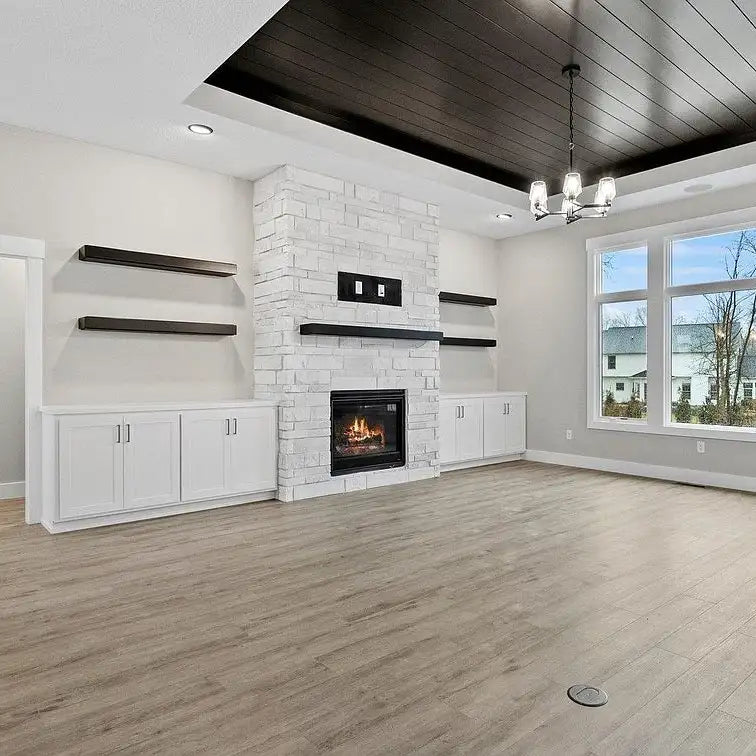 White stone fireplace with black accents and built-in cabinets.